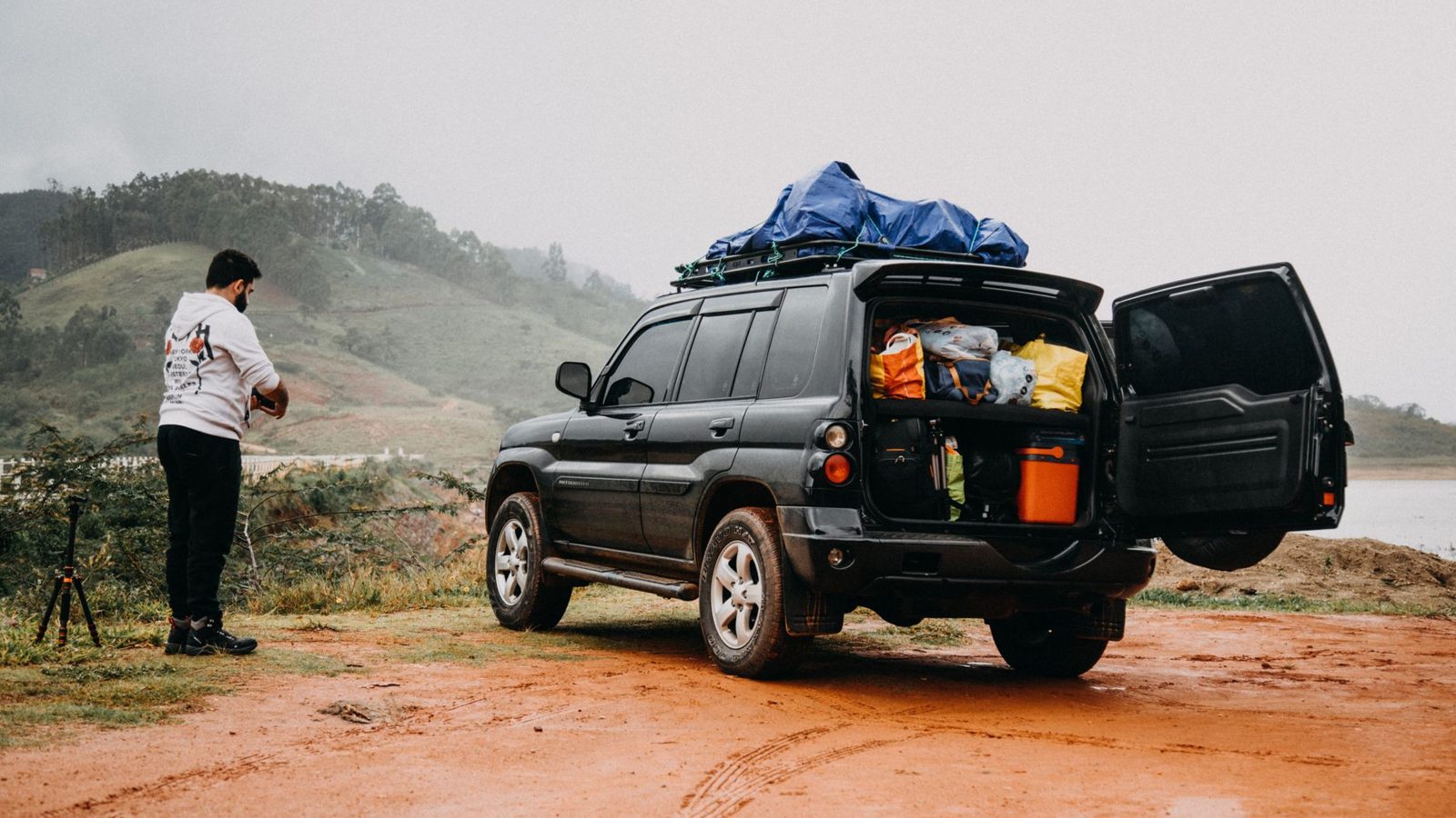 Man prepares for a foggy countryside adventure trip with a packed SUV.