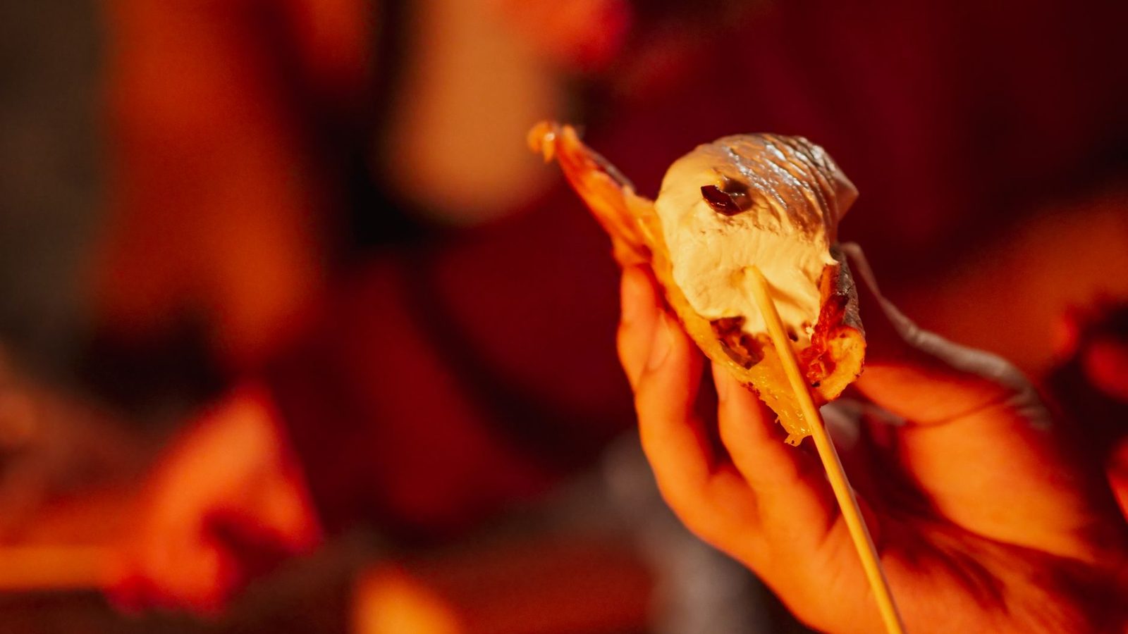 Delicious gooey smores with melted chocolate and marshmallow held by a hand, perfect for dessert lovers.