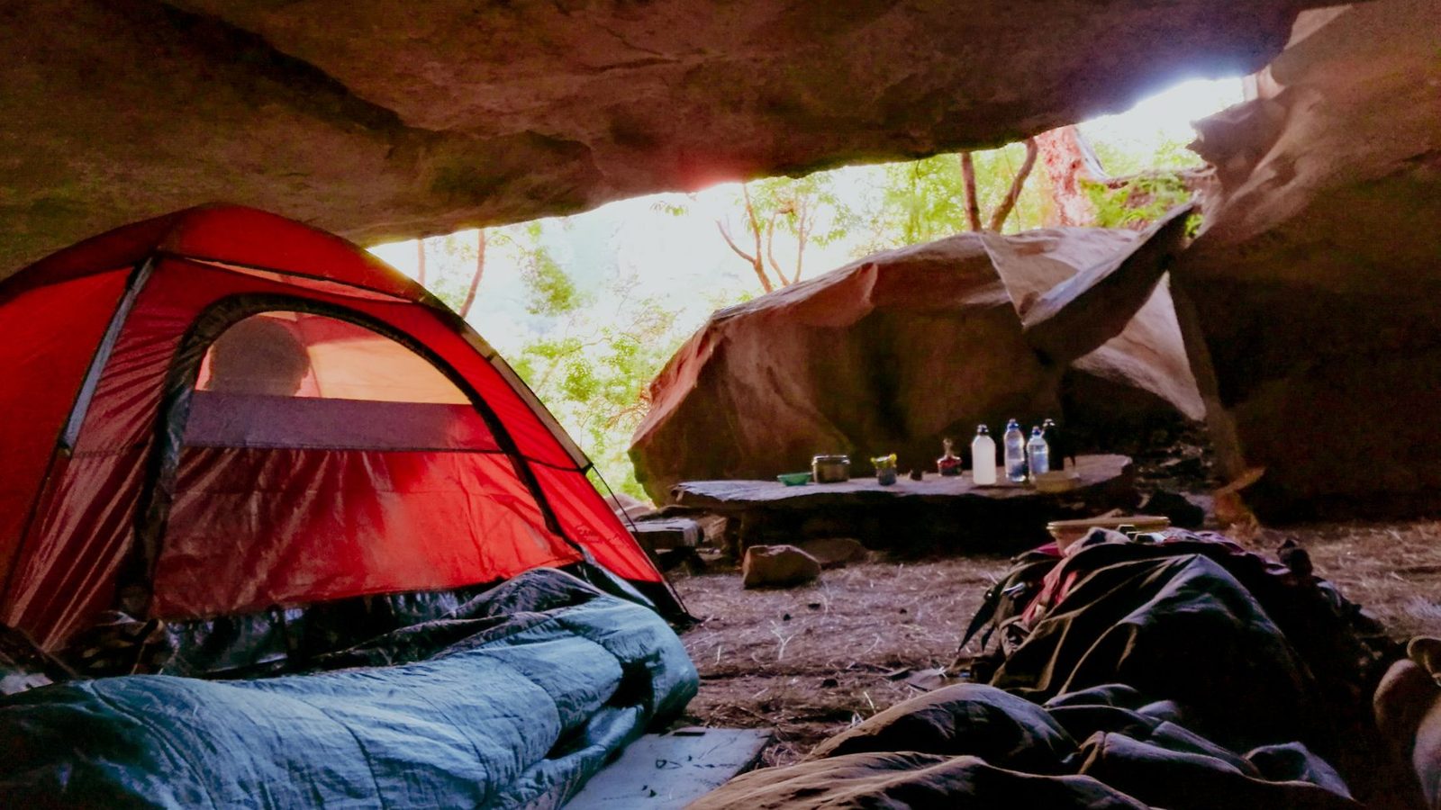 Explore the serenity of cave camping with a red tent in a natural setting, capturing relaxation and adventure.