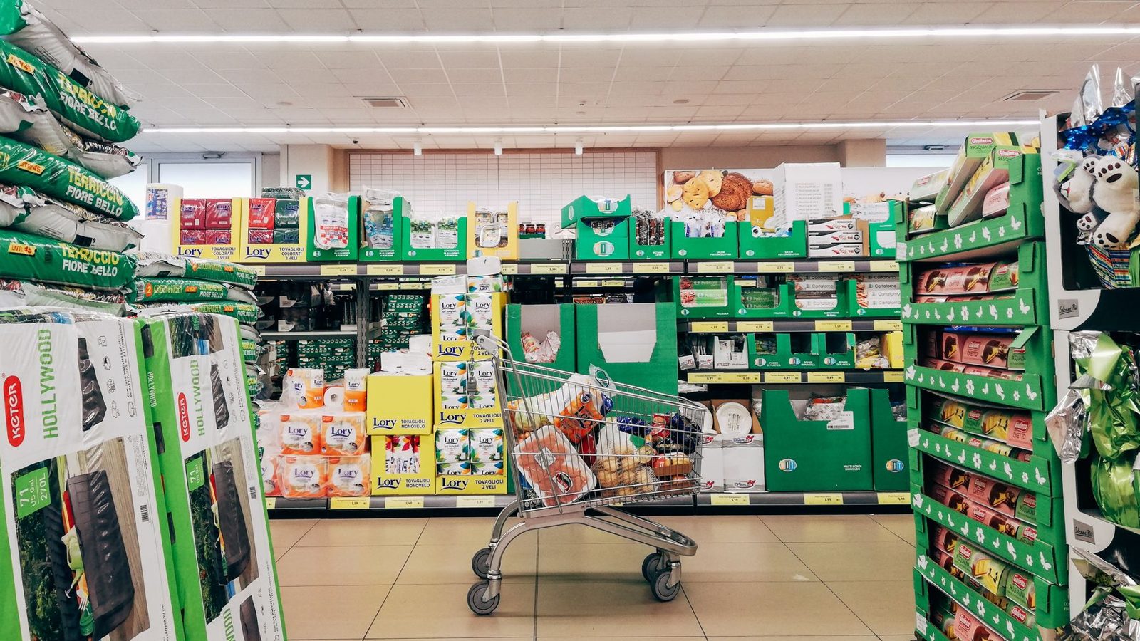 Shopping cart in a vibrant supermarket aisle in Padova, Italy.